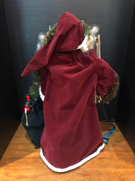 23" SANTA FIGURE IN LONG WINE COAT HOLDING WREATH AND BAG