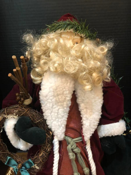 23" SANTA FIGURE IN LONG WINE COAT HOLDING WREATH AND BAG