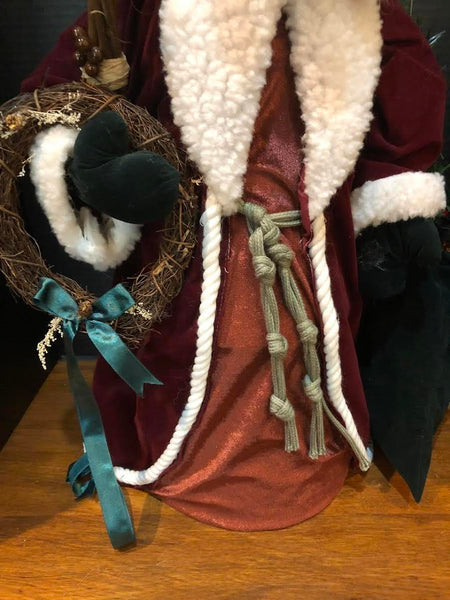 23" SANTA FIGURE IN LONG WINE COAT HOLDING WREATH AND BAG